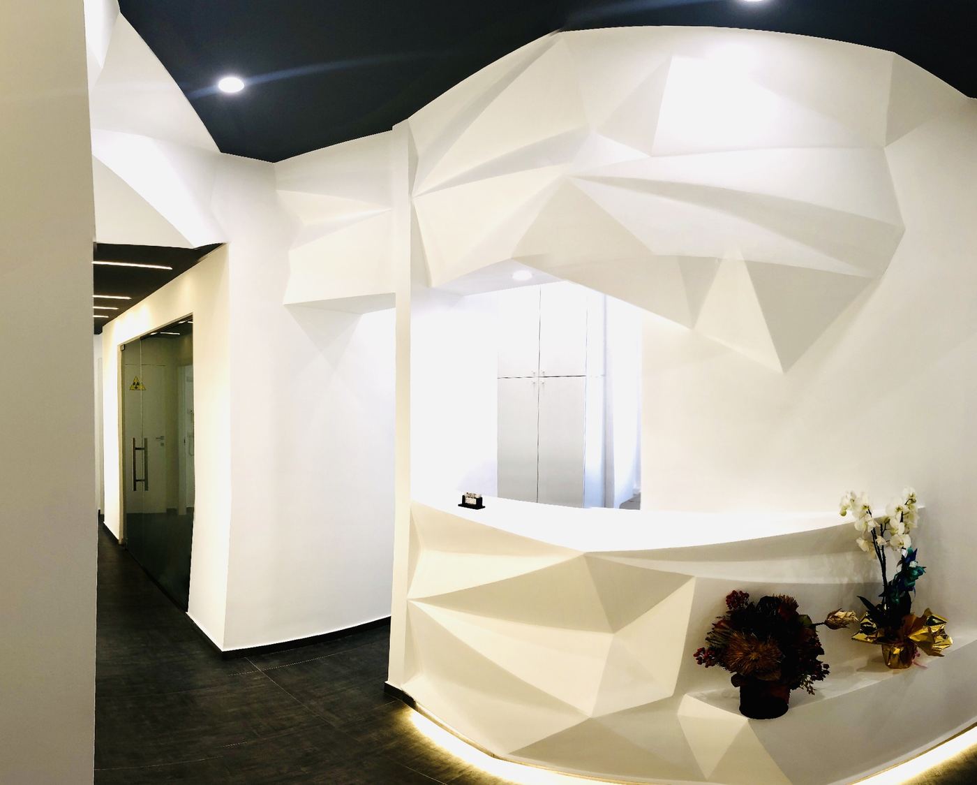 La reception dello studio, con il bancone bianco a spigoli e la luce a led